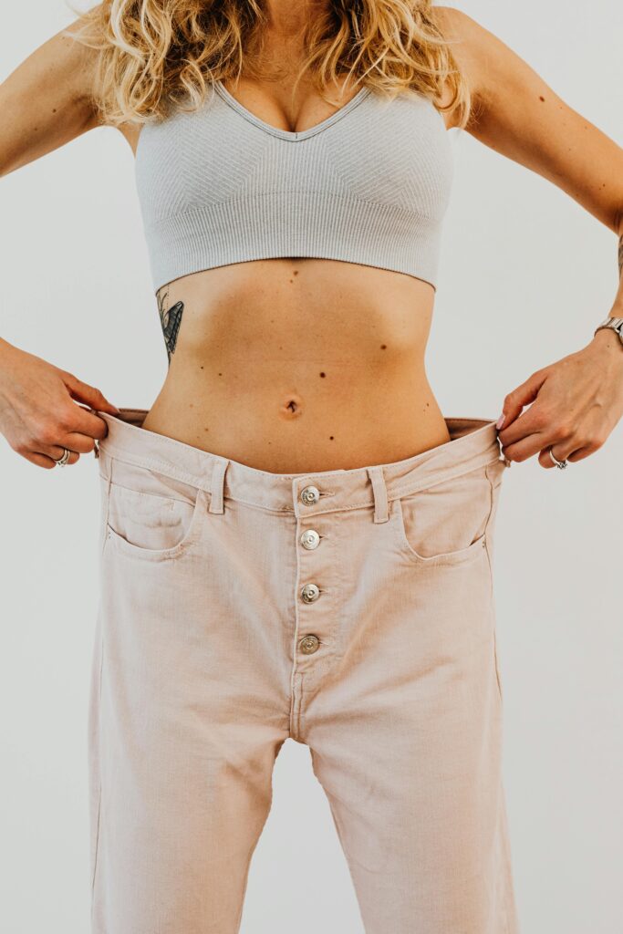 A woman showcases her weight loss journey by wearing loose-fitting trousers.